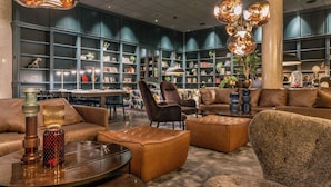 Una biblioteca moderna con sofás de cuero, una mesa de centro de vidrio y una gran estantería llena de libros y objetos decorativos.