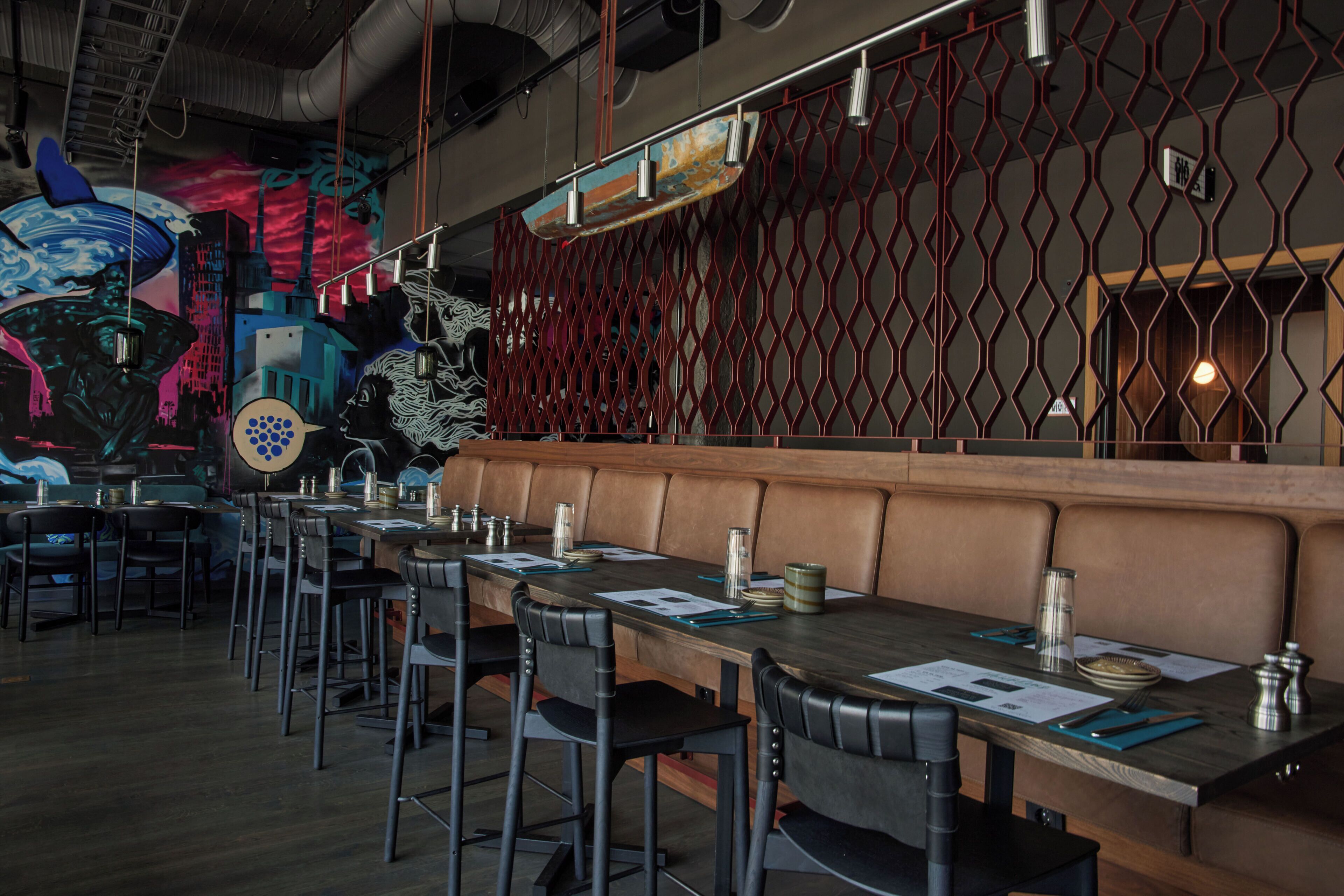 Un restaurante con una barra larga, mesas con cabinas y sillas altas.