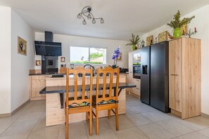 A modern kitchen with wooden cabinetry, a black refrigerator, and a dining area with two chairs.