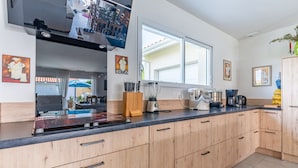 A modern kitchen with wooden cabinets, a black countertop, and various appliances. - Beautiful Villa 500 m from the Lake with Pool and Air Conditioning (Gastes)