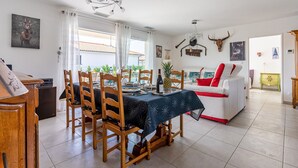 A dining area with a table set for four, wooden chairs, a chandelier, and a bull's head decoration on the wall. - Beautiful Villa 500 m from the Lake with Pool and Air Conditioning (Gastes)