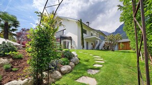 Une maison moderne dotée d’un jardin bien entretenu, d’un chemin en pierre et offrant une vue sur les montagnes.
