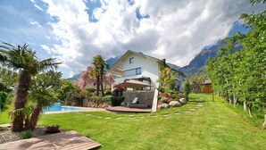 Une maison avec une piscine, une terrasse et une vue sur la montagne.