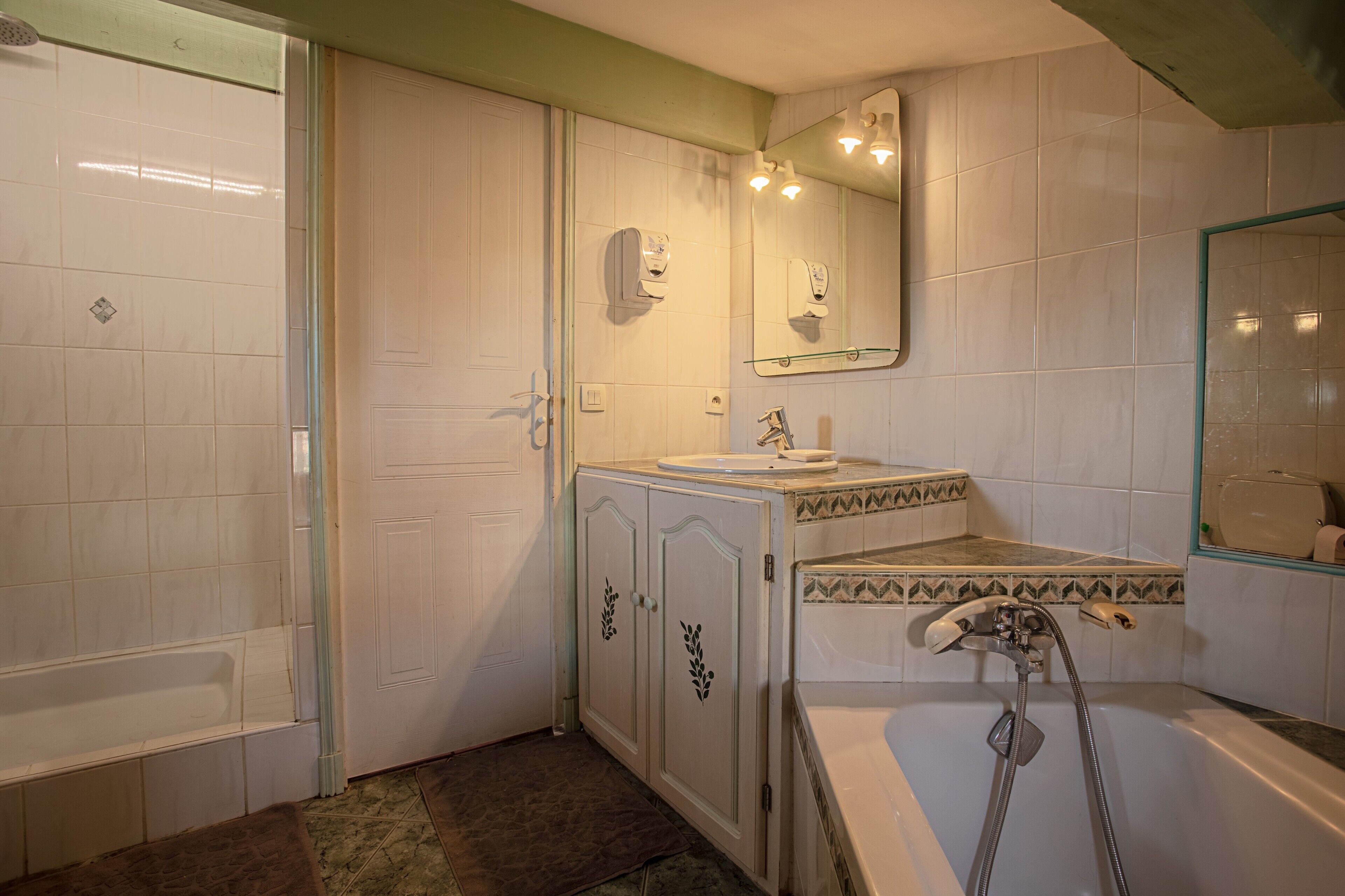 Un baño con bañera, lavabo, espejo y ducha.