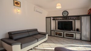 En moderne stue med sofa, fladskærms-tv, skab og et ur på væggen.