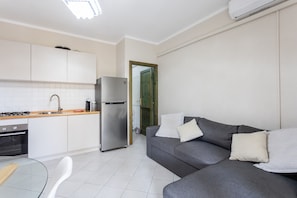 A modern kitchen with white cabinets, a stainless steel refrigerator, and a dining area with a glass table and white chairs. - Apartment 'Casamorle' with Private Terrace and Air Conditioning (Isola Rossa)