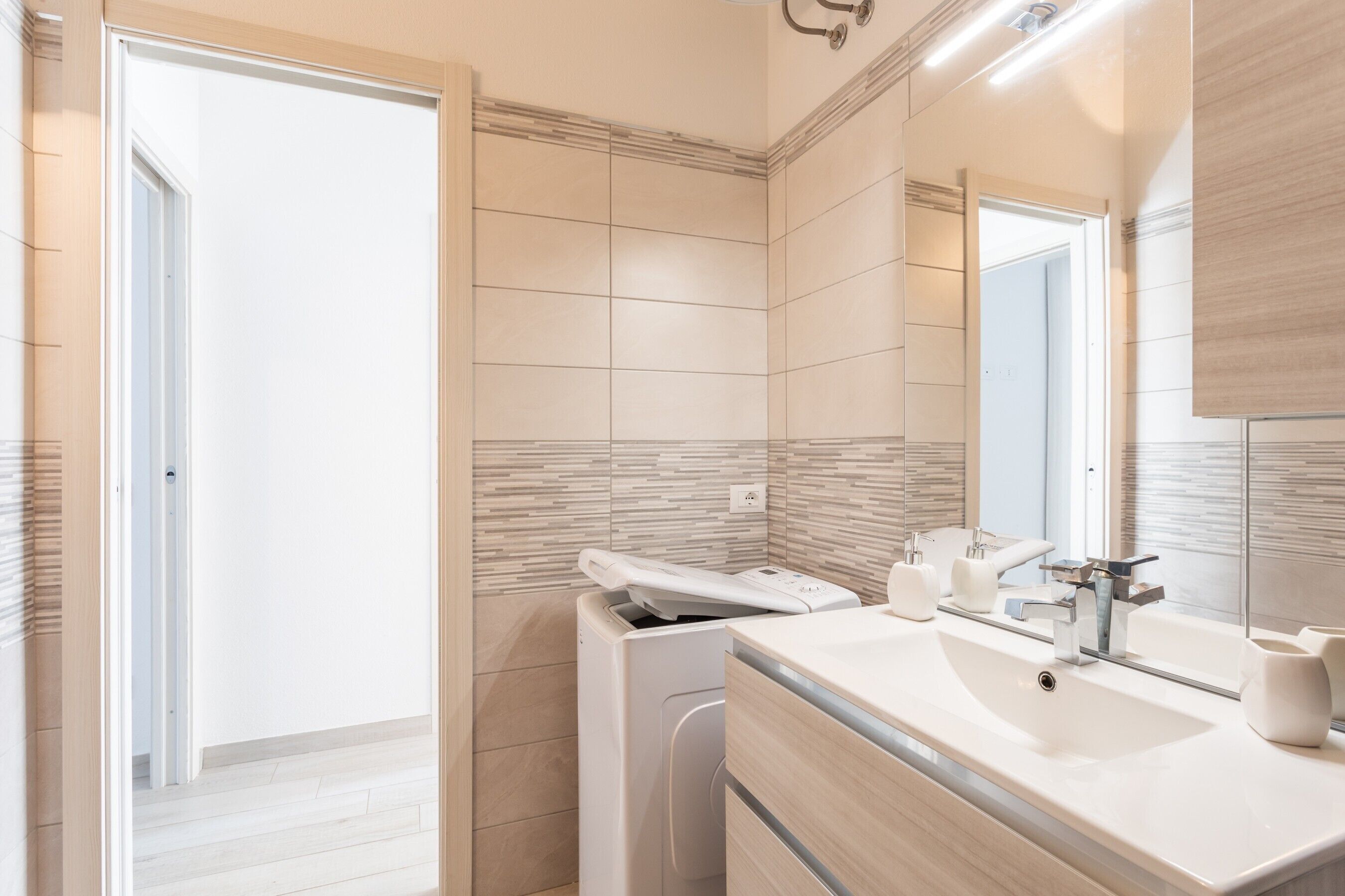 Un baño moderno con un espejo grande, un lavamanos y un inodoro.