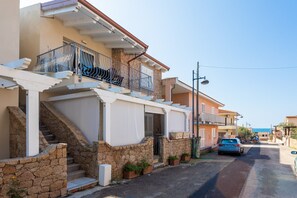 A residential street with stone steps, balconies, and a parked car.