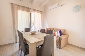 A dining area with a table, chairs, a bowl, and a sofa with pillows.