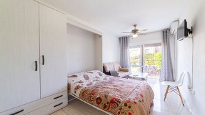 A bedroom with a bed, wardrobe, ceiling fan, and a view of the outside. - Studio 'Gaviotas 4' with Communal Pool, Wi-Fi, and Air Conditioning (Aguadulce)