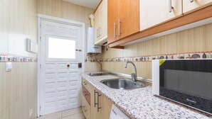 A compact kitchen with wooden cabinets, a double sink, and a built-in microwave. - Studio 'Gaviotas 4' with Communal Pool, Wi-Fi, and Air Conditioning (Aguadulce)