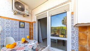 A dining area with a table set for two, a fan, and a view of greenery outside. - Studio 'Gaviotas 4' with Communal Pool, Wi-Fi, and Air Conditioning (Aguadulce)