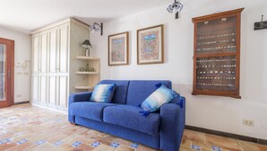 A room with a blue sofa, a cabinet, and a wall-mounted display case.