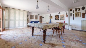 A dining room with a patterned tablecloth, wooden chairs, and a tiled floor.