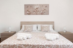 A neatly made bed with patterned bedding, two bedside tables with lamps, and a wall-mounted artwork above the bed.