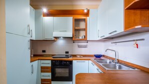 Una cocina compacta con armarios azul claro, encimera de madera, horno empotrado y pileta de acero inoxidable.