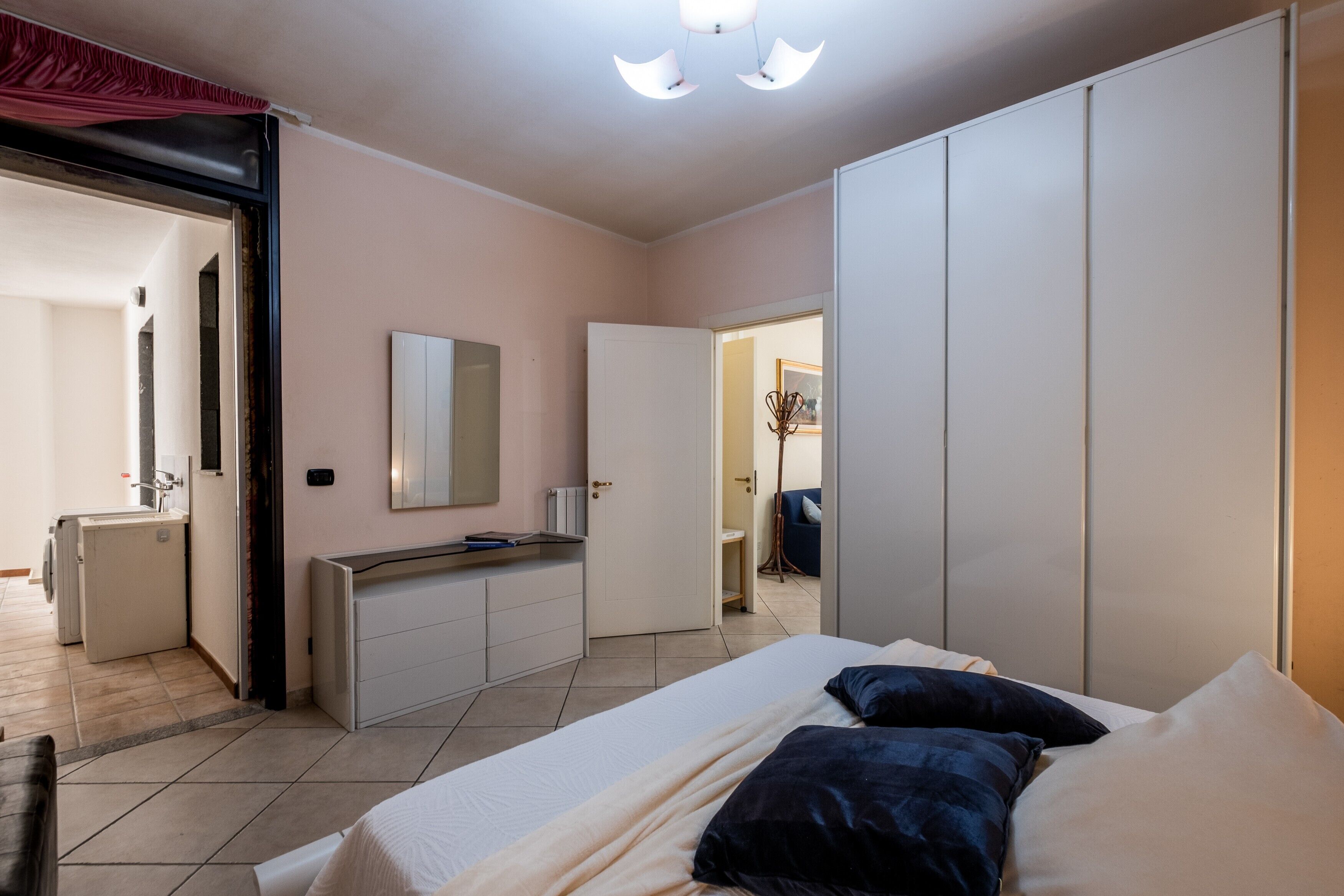 Ein Schlafzimmer mit Bett, Kleiderschrank, Spiegel und einer Küchenzeile.