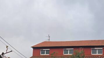 A red-roofed building with three windows and an antenna.