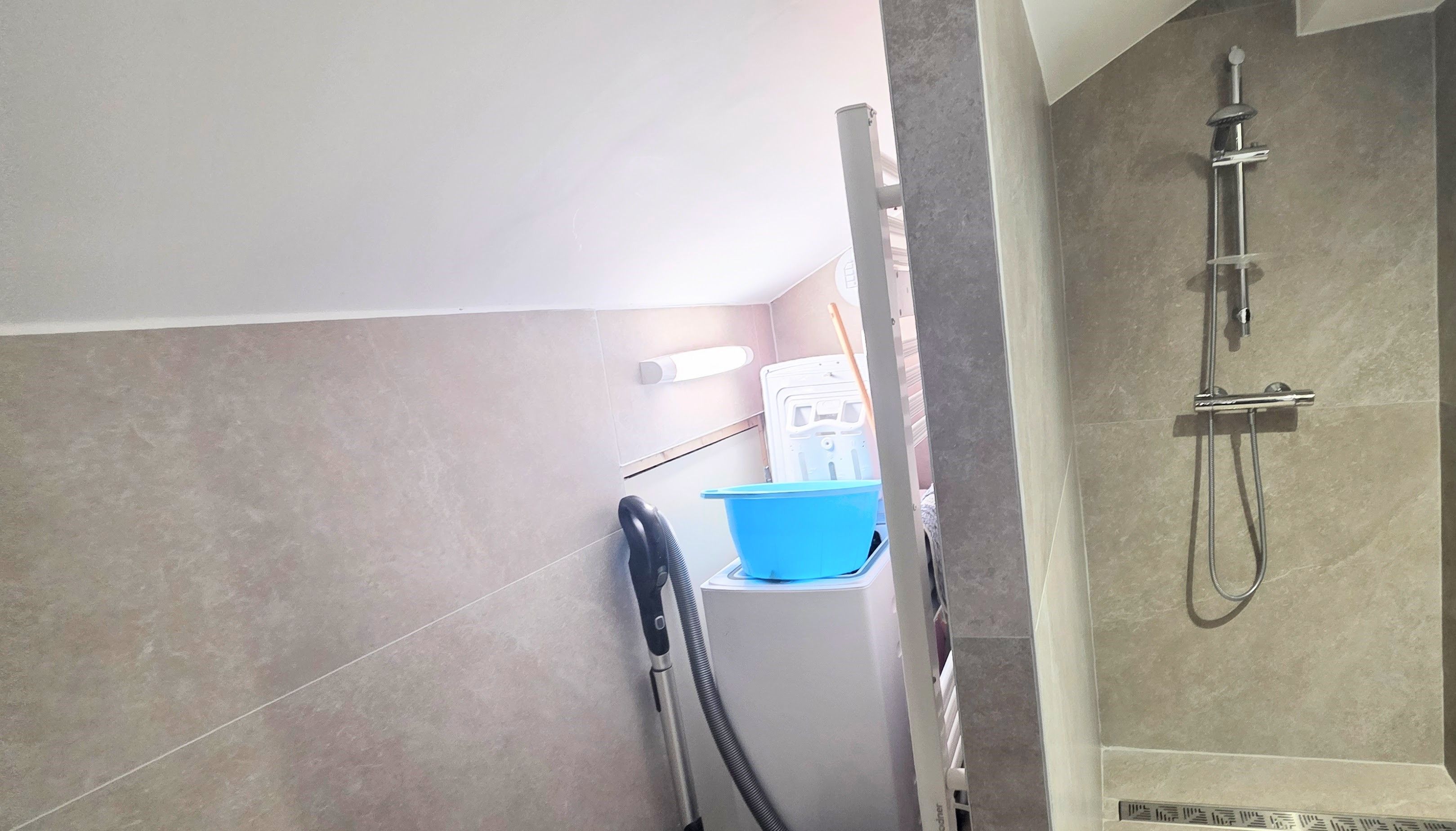 Ein Badezimmer mit Dusche, einem Handtrockner und einem blauen Waschbecken.