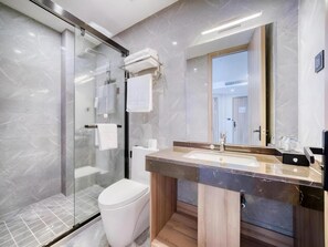 Une salle de bain moderne avec une douche à parois de verre, des toilettes blanches et un meuble-lavabo doté d’un plan de travail en marbre.