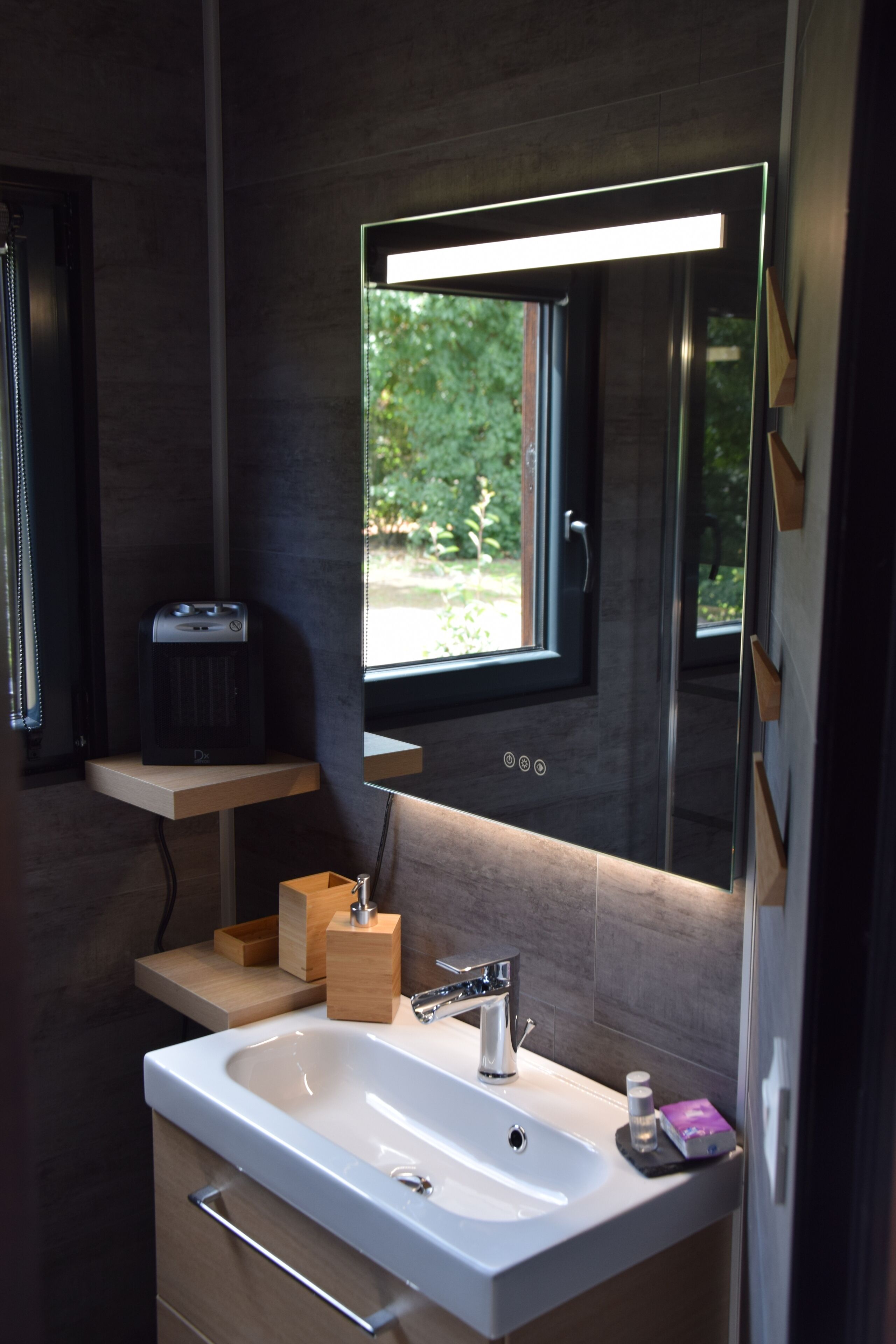 A modern bathroom with a white sink, a mirror, and a window.