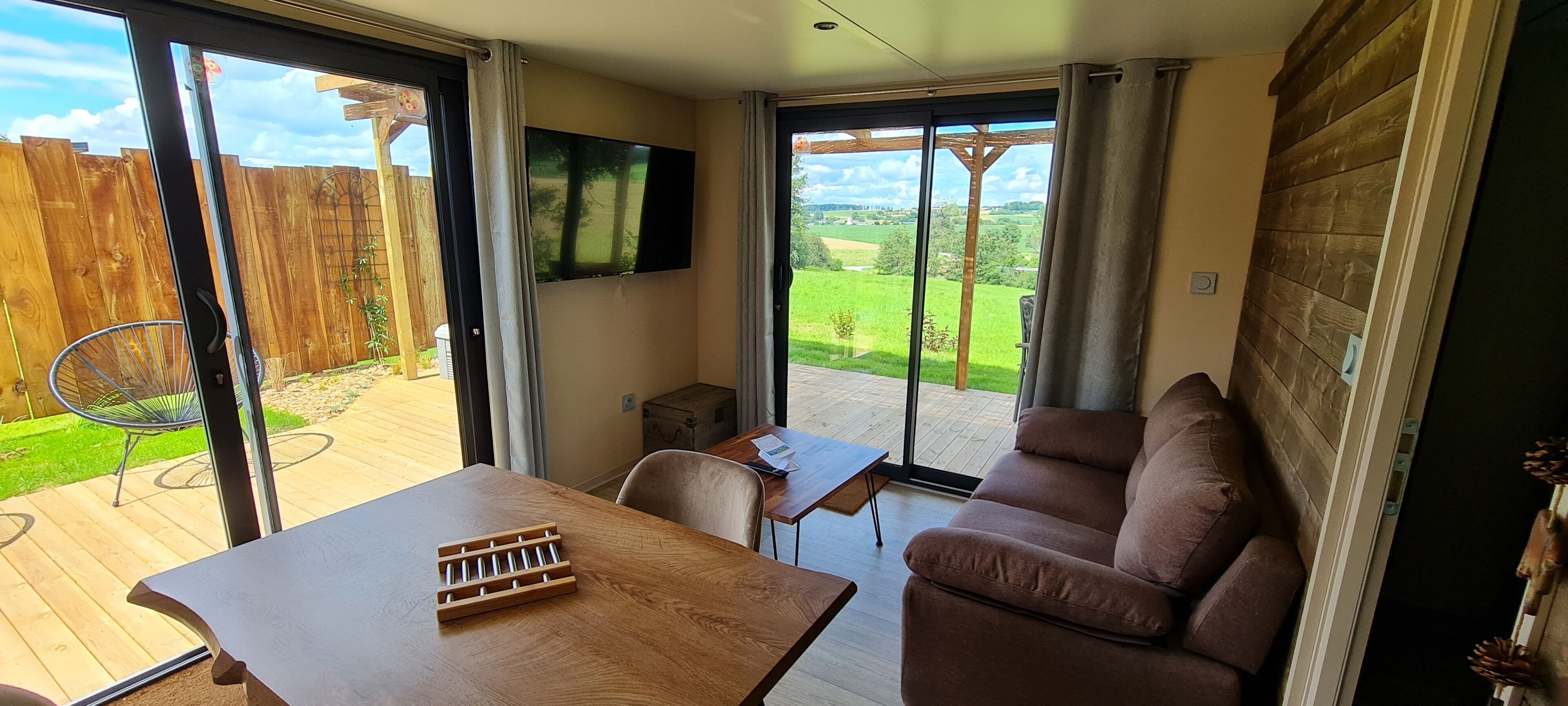 Una sala acogedora con un sofá, una mesa y un televisor instalado en la pared.