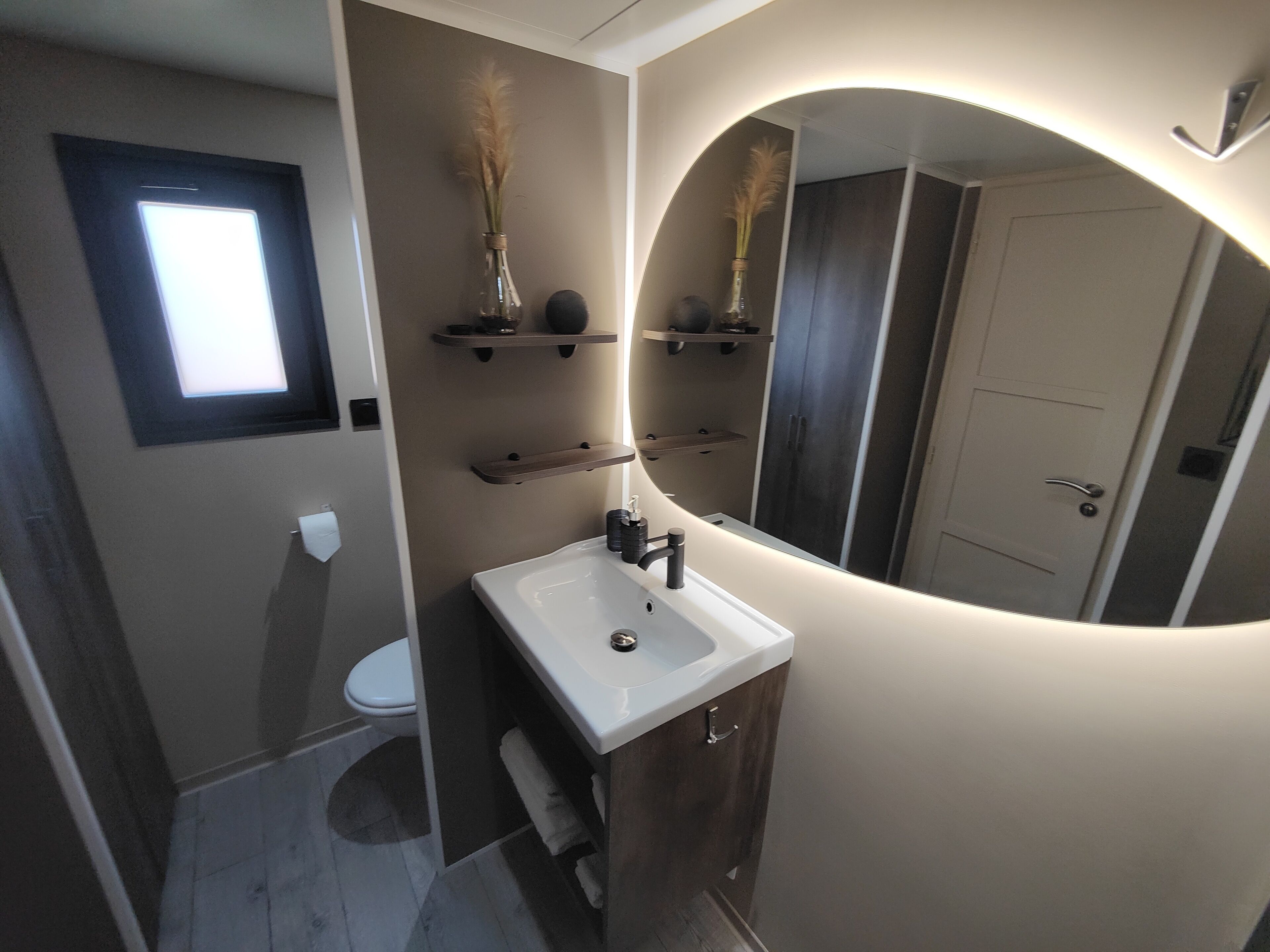 Een badkamer met een wit wastafel, donkere houten kastjes, een spiegel en een toilet.
