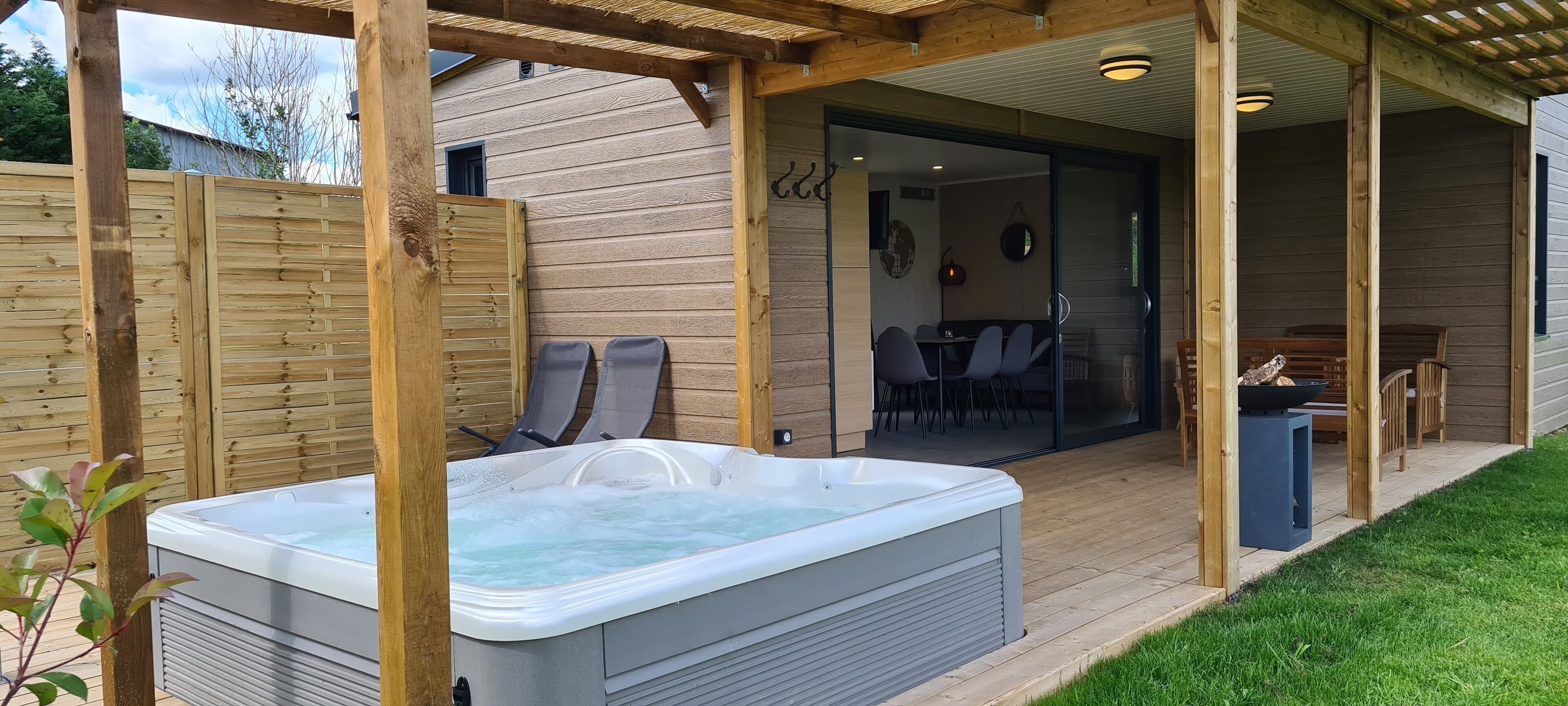 Eine Holzterrasse mit Whirlpool, Sitzgelegenheit im Freien und einer überdachten Patio.