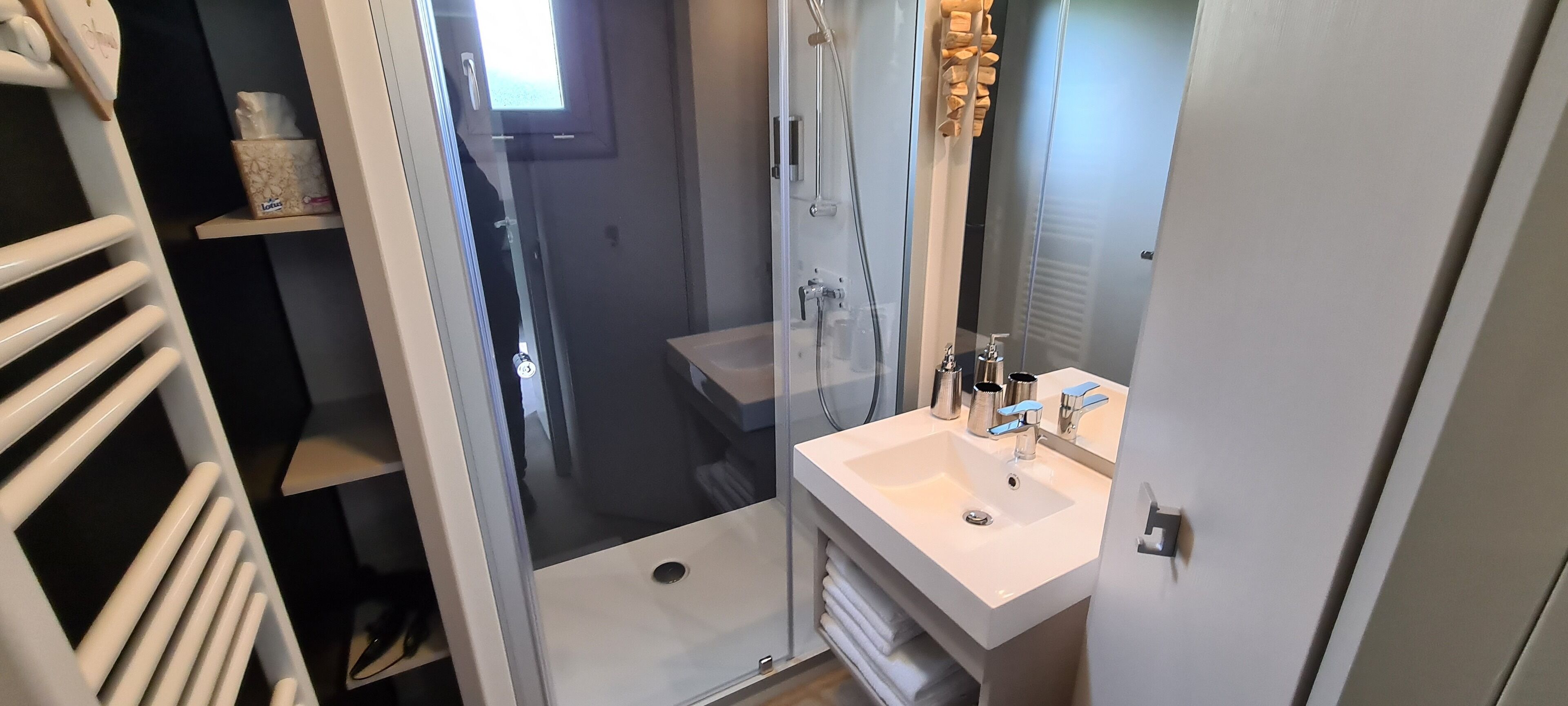 Un baño con lavabo blanco, espejo y toallero.