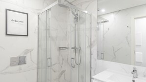 Une salle de bain moderne avec une douche en verre, un lavabo blanc et un sol carrelé en marbre.