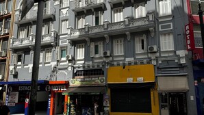 A multi-story hotel with balconies, a ground floor shop, and a street crossing. - Hotel Quintino (São Paulo)