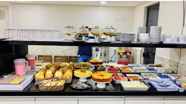 A buffet with various food items and glassware. - Hotel Quintino (São Paulo)