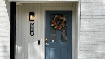 Une maison avec une porte bleue, un paillasson et un panneau indiquant le numéro de la maison.
