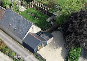 Un bâtiment doté d’un toit en pente, d’un jardin clôturé et d’une allée gravillonnée.