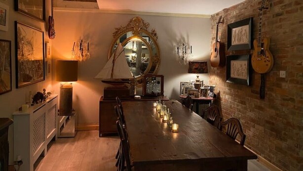 A dining area with a long wooden table, candles, and a mirror. - Eclectic Barn · Pergola & Dog-Friendly Garden (Calne)