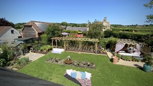 A backyard with a pergola, a small garden, and a patio area with outdoor furniture. - Eclectic Barn · Pergola & Dog-Friendly Garden (Calne)