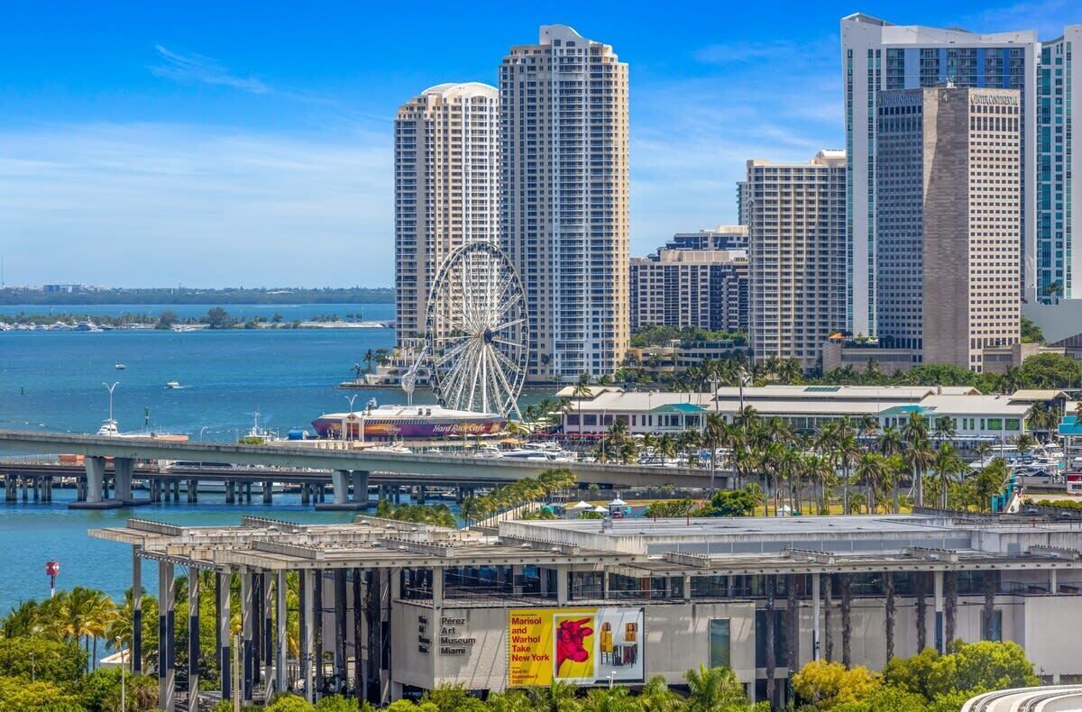 A high-rise hotel with a view of the ocean and a Ferris wheel in the background.