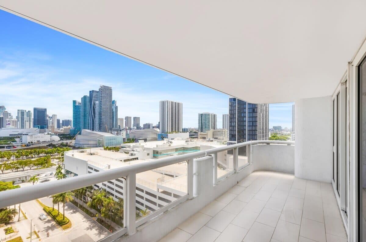 Ein Balkon mit Blick auf die Stadt, weißen Geländern und einem gefliesten Boden.