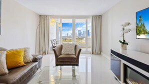 A modern living room with a sofa, armchair, and glass coffee table. - Bay Overlooking Condo | Downtown | StayCozy (Miami)
