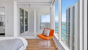 A modern hotel room with a large window, a balcony, and a view of the marina. - Bay View High-Rise | Private Balcony | StayCozy (Miami)