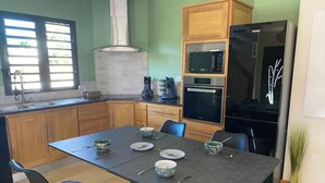 Cocina compacta con armarios de madera, microondas, horno y refrigerador negro.