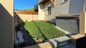 Una casa moderna con techo plano, un pequeño balcón y un césped cuidado.