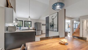 A modern kitchen with a central island, stainless steel appliances, and a dining area with a wooden table and chairs. -  Off Grid Mountain Retreat w/ Amazing Views (Idaho Springs)