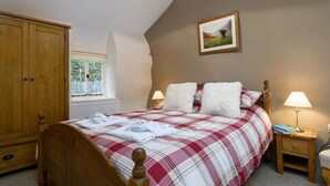 A bedroom with a wooden bed, a window, a painting, and a nightstand with a lamp. - Ceunant Bach - One Bedroom Cottage, Sleeps 2 (Bethesda)