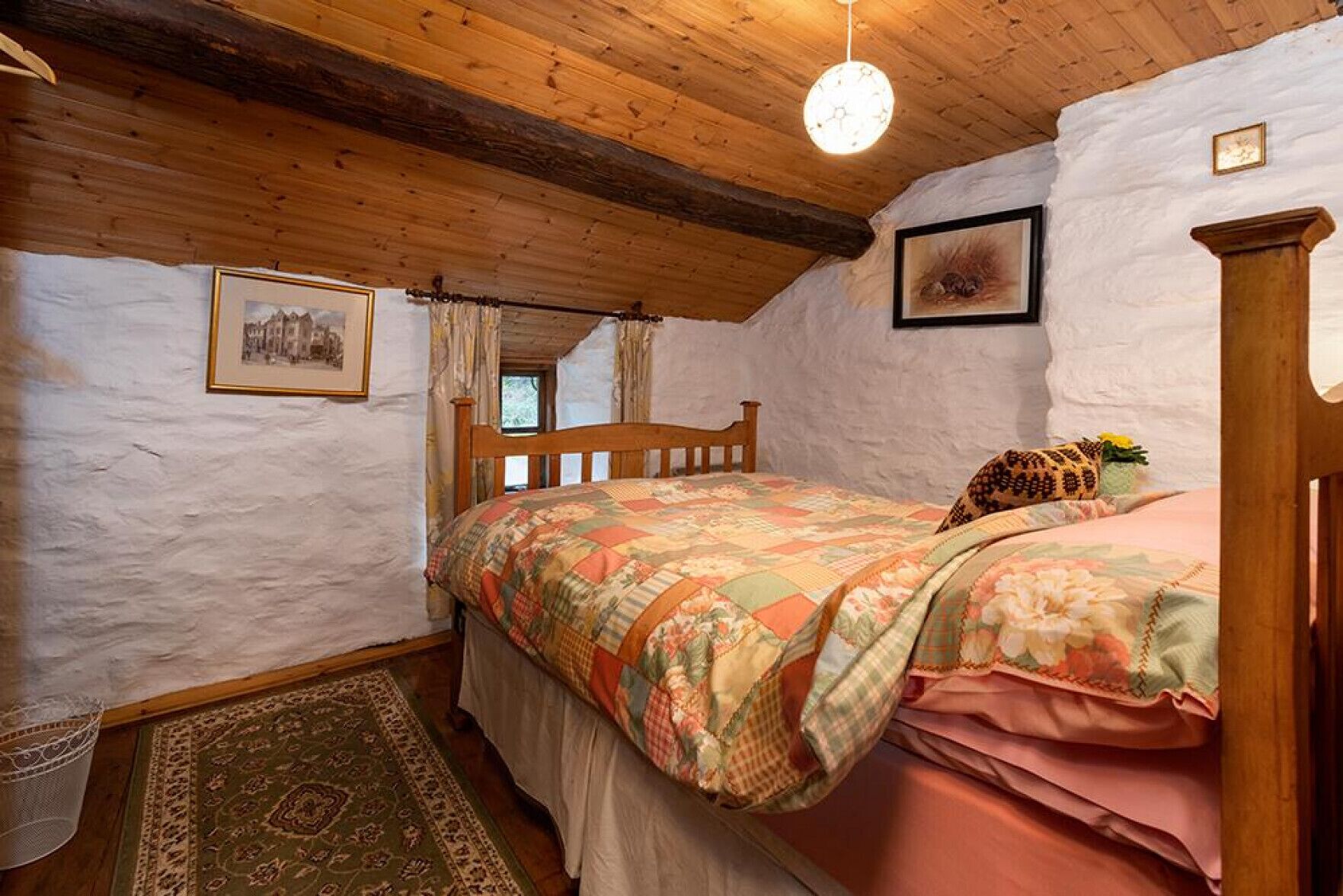 Une chambre confortable avec un lit en bois, une courtepointe à motifs et un plafond rustique.
