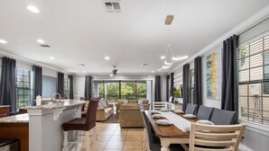 A spacious living area with a kitchen island, dining table, and seating. - Reunion Resort- Pool, Spa, Game Room, Disney, Golf Course, No resort Fees (Reunion)