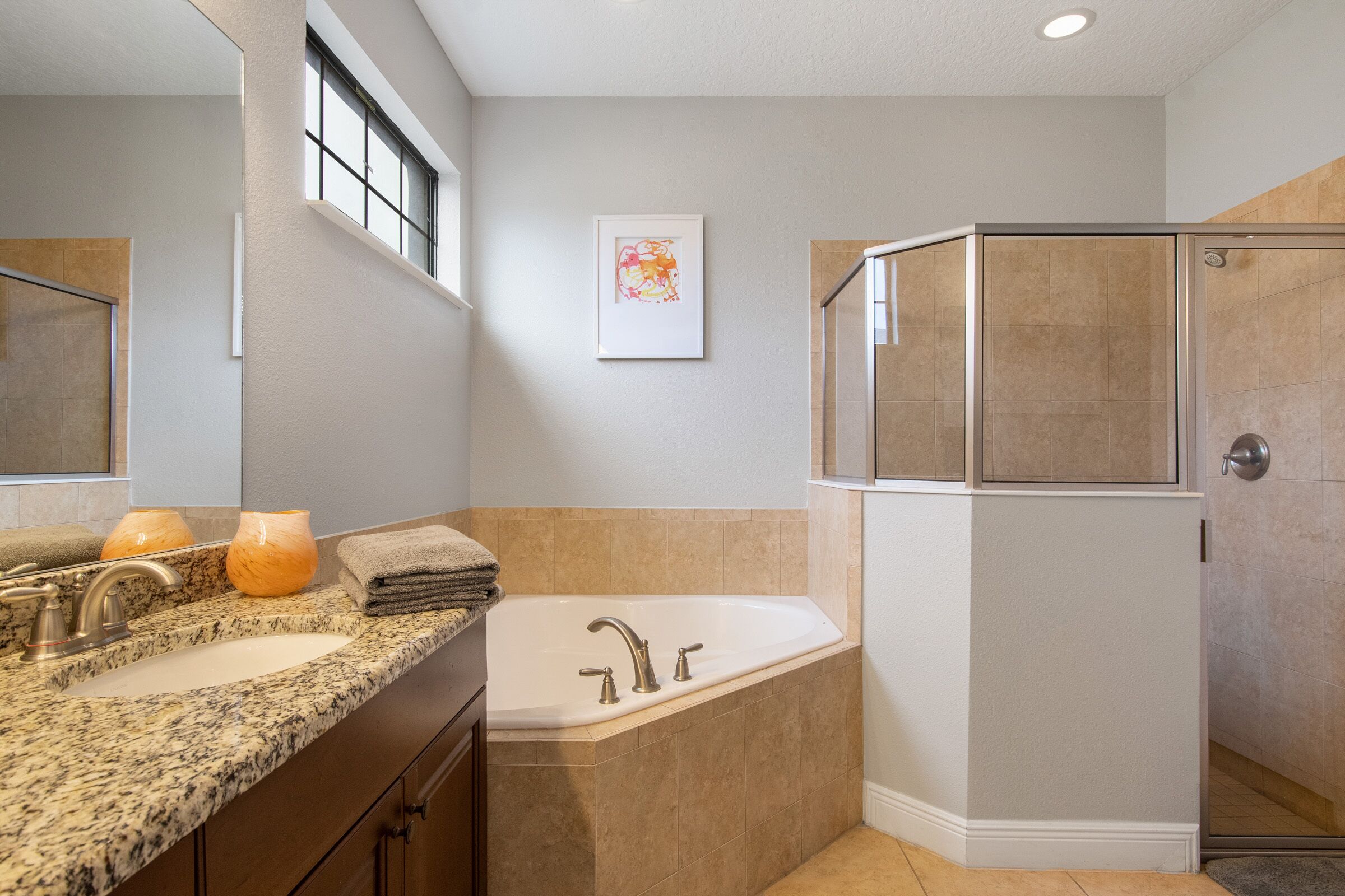 Une salle de bain moderne avec un comptoir en granit, un grand lavabo, une baignoire et une douche à l’italienne.