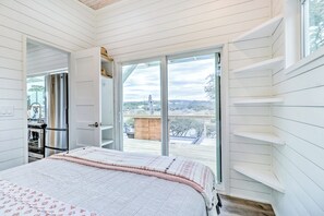 Une chambre dotée d’un grand lit, d’une porte-fenêtre coulissante donnant sur un balcon et offrant une vue sur l’extérieur.