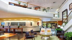 Un amplio vestíbulo con una recepción, zona de estar y una escalera que sube a un nivel superior.