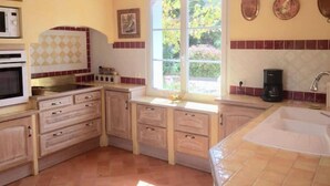 Eine kleine Küche mit Holdekor, einer Mikrowelle, einer Kaffeemaschine und einem Fenster für natürliches Licht.
